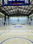 Cancha de baloncesto desde una perspectiva frontal mostrando el techo metálico
