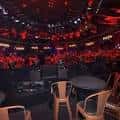 Interior del auditorio con iluminación roja y disposición de mesas y sillas para eventos