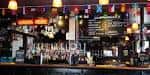 Interior del bar con el mostrador, grifos de cerveza y luces cálidas