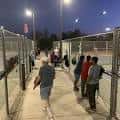 Área deportiva del parque con personas caminando junto a vallas metálicas