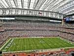 Interior del NRG Stadium durante un evento deportivo con campo de fútbol americano y gradas llenas