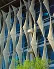 Detalle de la fachada con paneles geométricos y vegetación en primer plano