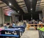 Interior del local con mesas largas y público asistiendo a un evento