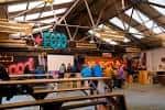 Interior del espacio con estructura metálica, cartel de 'FOOD' y personas en mesas