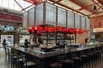 Vista interior del food hall con barra central y lámparas rojas colgantes