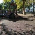 Área de juegos infantiles en un entorno arbolado dentro del parque