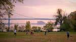 Espacio abierto del parque con personas caminando y puente al fondo