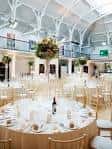 Sala preparada para evento con mesas redondas y decoración floral