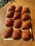 Plato de croissants recién horneados sobre mesa de madera en el establecimiento