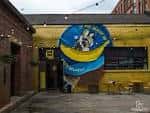 Vista exterior del local Banana Block con su distintiva fachada amarilla y mural