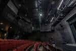 Interior del auditorio desde la perspectiva de las butacas, mostrando techo industrial y luces