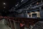 Filas de asientos en el auditorio con balcones laterales y paredes de ladrillo expuesto
