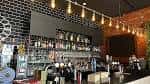 Interior del bar con estantería de botellas y luces colgantes