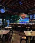 Interior del New Amsterdam con barra iluminada, luces ambientales y zona de mesas para celebraciones