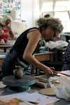 Interior del taller de cerámica con personas trabajando en torno
