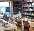Sala de clases con mesas y estanterías llenas de piezas de cerámica