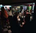 Vista interior del pub con clientes sentados en mesas durante la noche