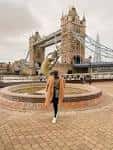 Persona caminando frente al Tower Bridge en un día nublado
