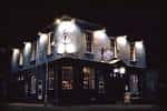 Fachada nocturna del pub The Washington con iluminación exterior