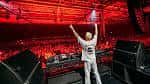 Escenario del Drumsheds con DJ actuando frente a una multitud bajo luces rojas