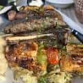 Plato de pescado asado con verduras y guarnición en mesa de restaurante