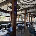 Interior del restaurante con mesas, sillas azules y techo de vigas de madera