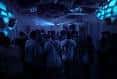 Interior del local con iluminación azul y gente asistiendo a un evento