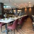 Sala de comedor con mesas largas y sillas tapizadas en rojo