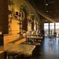Interior del bar con barra de mármol, espejos y mesas para clientes