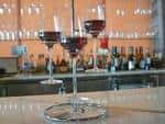 Detalle de dos copas de vino tinto sobre la barra con botellas de fondo