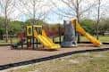 Área de juegos infantiles con toboganes amarillos y estructuras de madera en Plymouth Playground