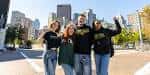 Grupo de estudiantes sonrientes frente al skyline de Pittsburgh en el campus