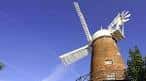 Detalle del molino de viento desde un ángulo bajo, mostrando sus aspas y estructura de ladrillo