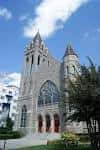 Vista exterior de la fachada principal de la iglesia con torres y ventanales góticos