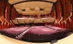 Interior del auditorio con butacas rojas y escenario iluminado