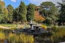 Paisaje del jardín con árboles de otoño y una fuente central