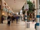 Pasillo interior del centro comercial con personas caminando y decoración de plantas