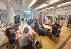 Sala de eventos o reuniones con personas sentadas alrededor de mesas largas