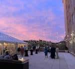 Vista del patio exterior durante el atardecer con invitados y decoración de luces