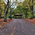 Sendero arbolado en Burley Park con un kiosco al fondo