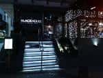 Entrada principal del Blackhouse Gastrobar por la noche, mostrando las escaleras iluminadas y el letrero del local