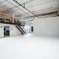 Interior del espacio de eventos con paredes blancas y estructura industrial