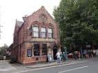 Exterior del pub con clientes en la acera y entorno urbano