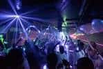 Interior del bar con iluminación de discoteca y público bailando
