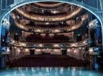 Vista panorámica del interior del Novello Theatre con múltiples niveles de balcones y butacas rojas