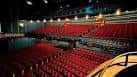 Interior del auditorio con butacas rojas y escenario