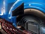 Vista panorámica del interior del teatro con iluminación azul y butacas rojas