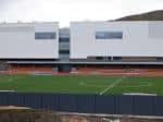 Vista exterior del Meadowbank Sports Centre con campo de fútbol y fachada moderna