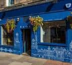 Fachada azul del Home Bar en Edinburgh con macetas colgantes
