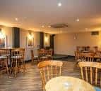 Interior del bar con mesas de madera y sillas tipo Windsor